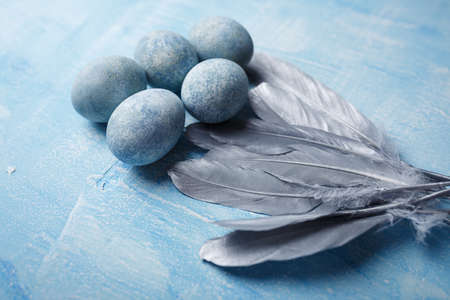 Beautiful painted easter eggs and silver feathers on blue background. Close up shotの写真素材