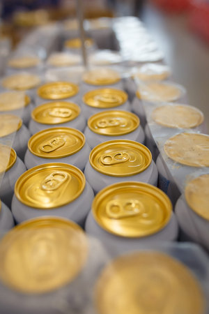 Soft focused close up shot of canned beer, lemonade or soda pop in plastic package. Top of cans with...