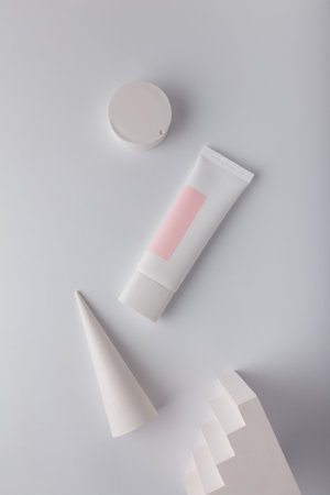 Cream tube with pink blank label, no brand mockup on white background with geometric concrete decor. Tender minimal compositionの写真素材