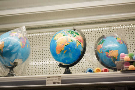 Two globes in packages, one classroom globe model with Ukrainian inscriptions on supermarket shelf. Geographic educationの写真素材