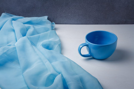Big blue cup with blue fabric on white background. Beautiful colors combination of still life