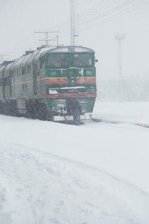 Izmail, Ukraine. February 2022. Driver checking train on railway station covered with snow. Blizzard, snowstorm, transportation conceptのeditorial素材