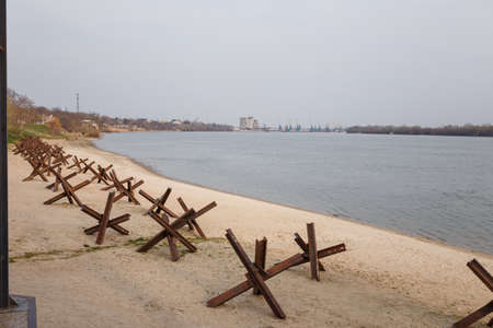 Metallic military obstacles, anti tank hedgehoges on bank. Constructions protecting freedom, independence of Ukraine 2022の写真素材