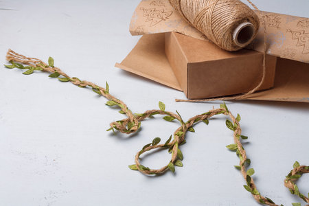 Natural earth-colored paper and eco-friendly decorative elements for Christmas presents wrapping, jute rope spool on white tableの写真素材