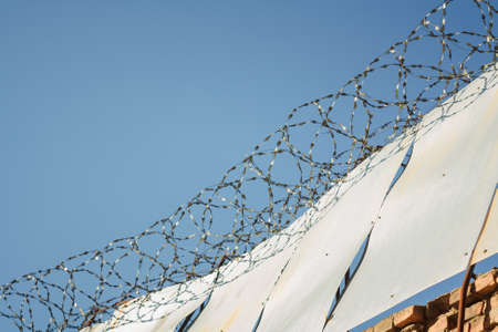 barbed wire on the prison wall, blue sky backgroundの写真素材