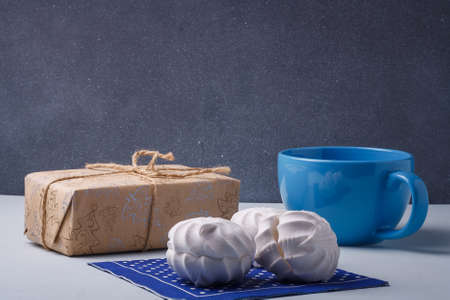 Merry Christmas wrapped present, blue cup, fresh sweet zephyr, marshmallows on blue napkin. Festive holidays, sweets.の写真素材