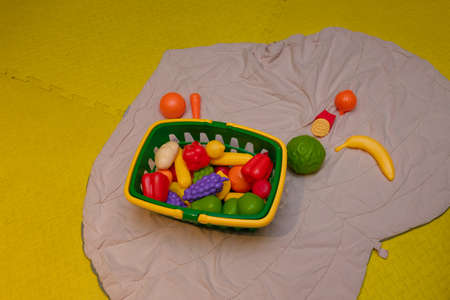 Basket of plastic vegetables toys on carpet in child room. Educational toys, early development, preschool activity.の写真素材