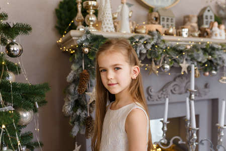 Beautiful little girl in white dress on decorated Merry Christmas backgroundの写真素材