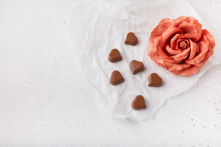 14 February Heart shaped chocolates, fabric rose on white paper background, copy space. Valentines...