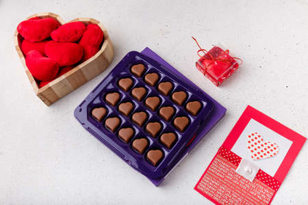 box of heart shaped chocolates, postcard, red candle, wooden box of fabric hearts on white. Valentines day 14 February presentの写真素材