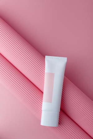 Cosmetics mock up on pink paper background. Cream tube template with no brand. Tender face skin care. Place for text, vertical shotの写真素材