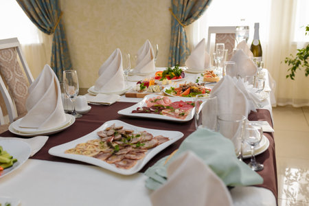 Festive table with appetizers. Salads, cheese and meat plates with vegetables and greenery. Empty...