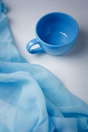 Big blue cup with blue fabric on white background. Beautiful colors combination of still lifeの写真素材