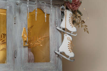 Wooden skates toy hanging on cupboard decorated with fir branches, icycles and snowy roses. merry Christmas decorated elementsの写真素材