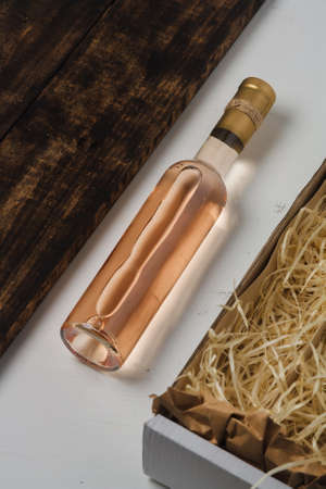 250 ml bottle of white wine with blank label. Chardonnay, riesling, sauvignon blanc. Box with wooden shavings. Vertical shotの写真素材