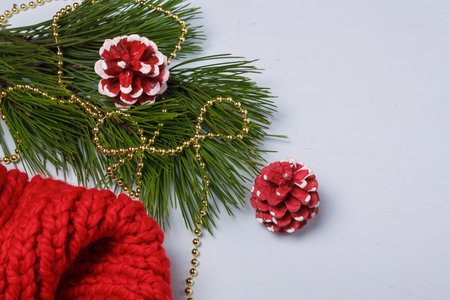 Red knitting, pine branch, red painted cones, golden beads on light background. Christmas concept. Copy spaceの写真素材