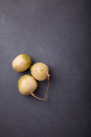 Three whole fresh watermelon radish, daikon root vegetables with white skin and purple inside on grey wooden background. Top view, copy spaceの写真素材