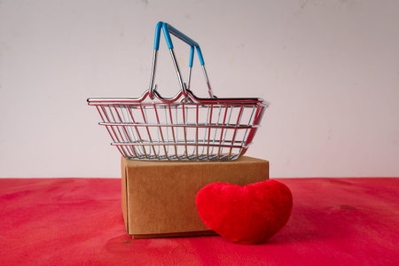 Shopping basket with red heart soft foy, box on bright background. Valentines day sale, buying...