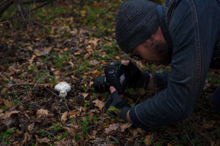 Izmail, Ukraine. October 2020. Man making photo of tiny mushroom in forest using camera and flash light. Macro world photography, nature landscape.の写真素材
