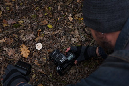 Izmail, Ukraine. October 2020. Unrecognizable man making photo of tiny mushroom in forest using...