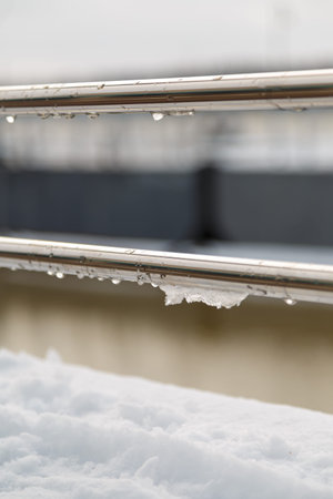 handrail, railing with water drops and wet snow build-up. early spring weather conditions, thaw and snow meltingの写真素材