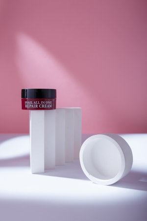Izmail, Ukraine. May 2022. Brown container of korean Eyenlip Snail All In One Repair Cream on pink backdrop, white concrete decorationsのeditorial素材