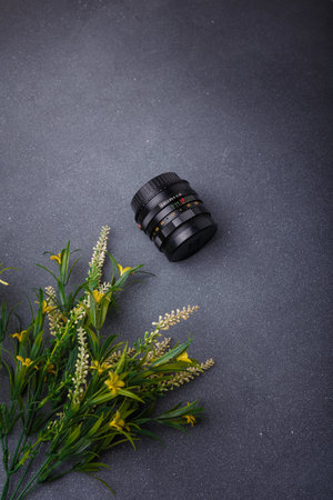 Izmail, Ukraine. April 2022. USSR Helios lens for photo camera on grey background with yellow flowers. Old photo equipment, lens brandのeditorial素材