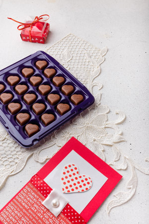 Izmail, Ukraine. 14 February 2022. Violet box of heart shaped chocolates Milka and postcard on white background. Valentines day sweetsのeditorial素材