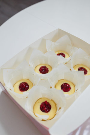 Box of not ready cupcakes. Pastry with jam layer without cream in white paper cover on table, top...