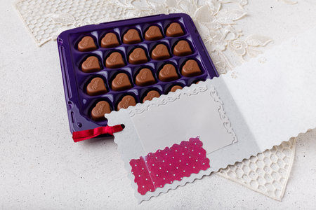 Izmail, Ukraine. 14 February 2022. Violet box of heart shaped chocolates Milka and postcard on white background. Valentines day sweetsのeditorial素材