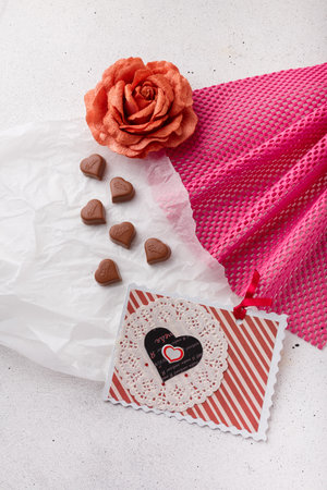 Izmail, Ukraine. 14 February 2022. Heart shaped chocolates Milka, fabric rose and postcard on white paper. Valentines day sweetsのeditorial素材