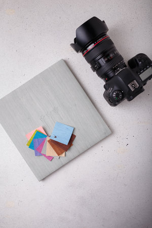 Izmail, Ukraine. April 2022. Canon EOS photo camera with L series zoom lens, album with grey leather cover samples on white background, copy spaceのeditorial素材
