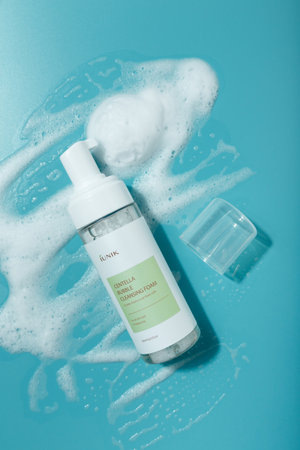Izmail, Ukraine. March 2022. IUNIK Centella bubble cleansing foam bottle on blue background. Korean face skin care cosmetics textureのeditorial素材