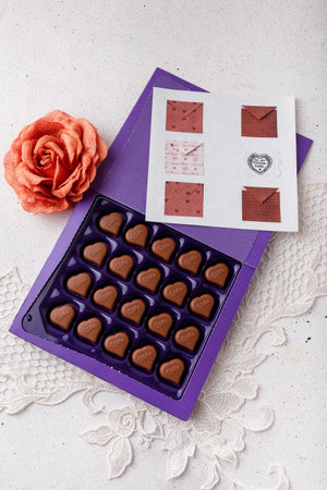 Izmail, Ukraine. 14 February 2022. Violet box of heart shaped chocolates Milka, rose, postcard on white. Valentines day sweetsのeditorial素材