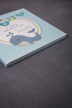 Izmail, Ukraine. June 2020. Baby photo album or photobook with blue whale on grey background. Inscription: Artem 1 year, 12 June, some dataのeditorial素材