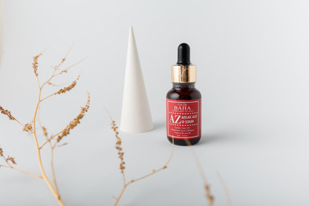 Izmail, Ukraine. March 2022. Baha cosmetics. Brown bottle of azelaic acid on white background with geometric concrete decorative element. Skin careのeditorial素材