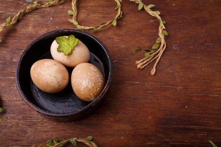 Black bowl with brown colored Easter eggs on rustic background. Spring, Easter concept. Top view,...