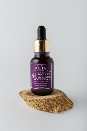 Izmail, Ukraine. March 2022. Baha cosmetics. Bottle of salicylic acid on wooden cut on white background. Face skin care, copy spaceのeditorial素材