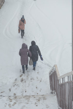 Izmail, Ukraine. February 2022. People walking down the stairs covered with snow on snowy winter day. Blizzard, vertical shotのeditorial素材