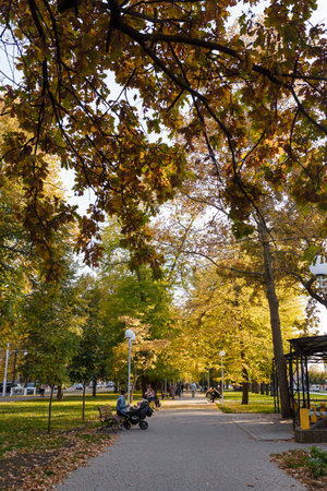 Izmail, Ukraine. September 2021. Beautiful Ukrainian town park, autumn landscape with street lamps, benches and people having restのeditorial素材