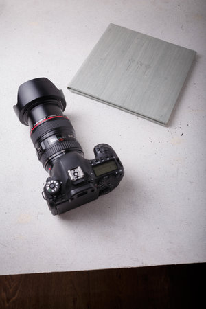 Izmail, Ukraine. April 2022. Canon EOS photo camera with L series zoom lens 24-105 mm and album with grey leather cover on white background, copy spaceのeditorial素材