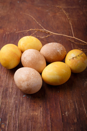 Vertical close up shot of colored easter eggs on brown rustic tableの写真素材