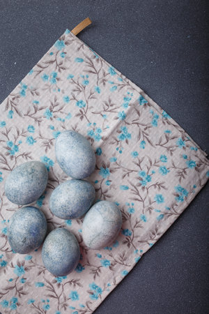 Easter eggs DIY painted blue on grey wooden background with kitchen towel. Top view, copy space, vertical shotの写真素材