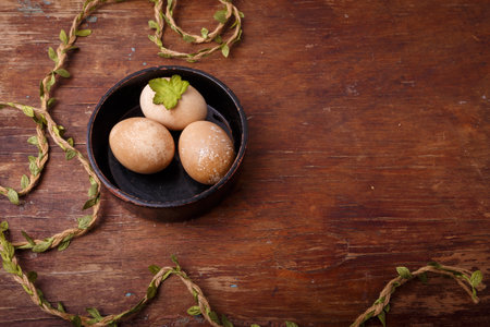 Black bowl with brown colored Easter eggs on rustic background. Spring, Easter concept. Top view, copy spaceの写真素材