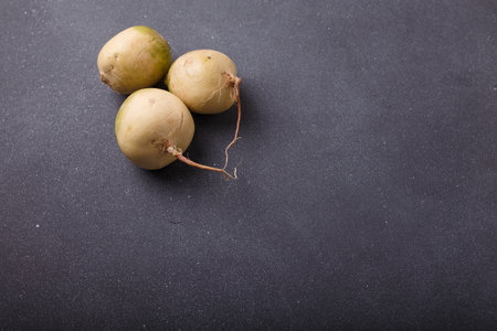 Three whole fresh watermelon radish, daikon root vegetables with white skin and purple inside on grey wooden background. Top view, copy spaceの写真素材