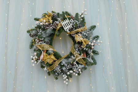 beautiful christmas wreath with white berries on fir branches, golden ribbon and cones hanging on...