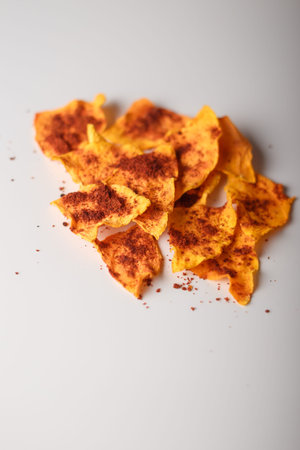 Heap of dried pumpkin slices, dry vegetable crisps, chips pile with pepper and paprika on white...