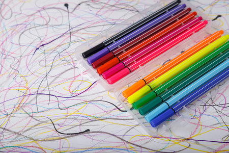 Multicolored marker or fine liner pens in plastic case on paper background. Art tools.
