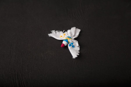 White dove, symbol of peace with Ukrainian national flag colored embroidery stitches. Textile brooch on black wooden background, copy space.の写真素材