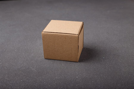 Cardboard box, square brown cardton container on gray background. No brand, no label. Copy space....